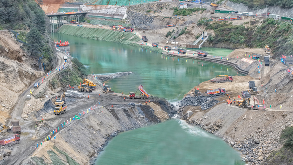 1.牙根一级水电站龙口合陇即将成功,数十辆自卸汽车来回不间断运输石料进行填筑.jpg
